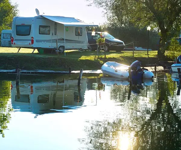 See mit Booten und einem Wohnwagen auf einem Campingplatz - Verkaufsangebot von CampConsult